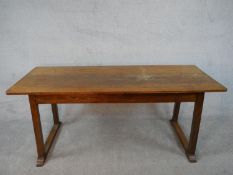 A Heals style Arts and Crafts oak refectory dining table on square trestle supports resting on