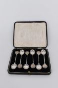 A cased set of silver tea spoons by James Fenton, each of the finials in a relief medal design