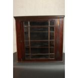 A George III mahogany corner cabinet, with a glazed door enclosing shelves. H.74 W.78 D.41cm.
