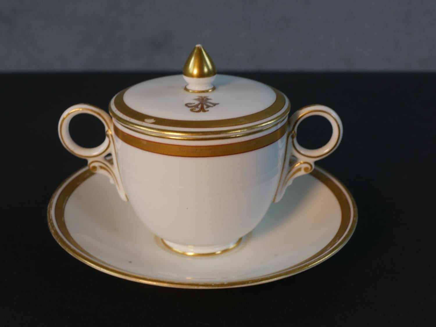 A 19th century Crown Derby gilded porcelain lidded twin handled hot chocolate cup and saucer. Each