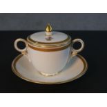 A 19th century Crown Derby gilded porcelain lidded twin handled hot chocolate cup and saucer. Each