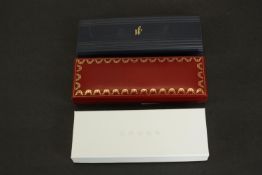 Three pens in boxes, including a cased Cartier "must de Cartier" steel-coloured lacquered metal