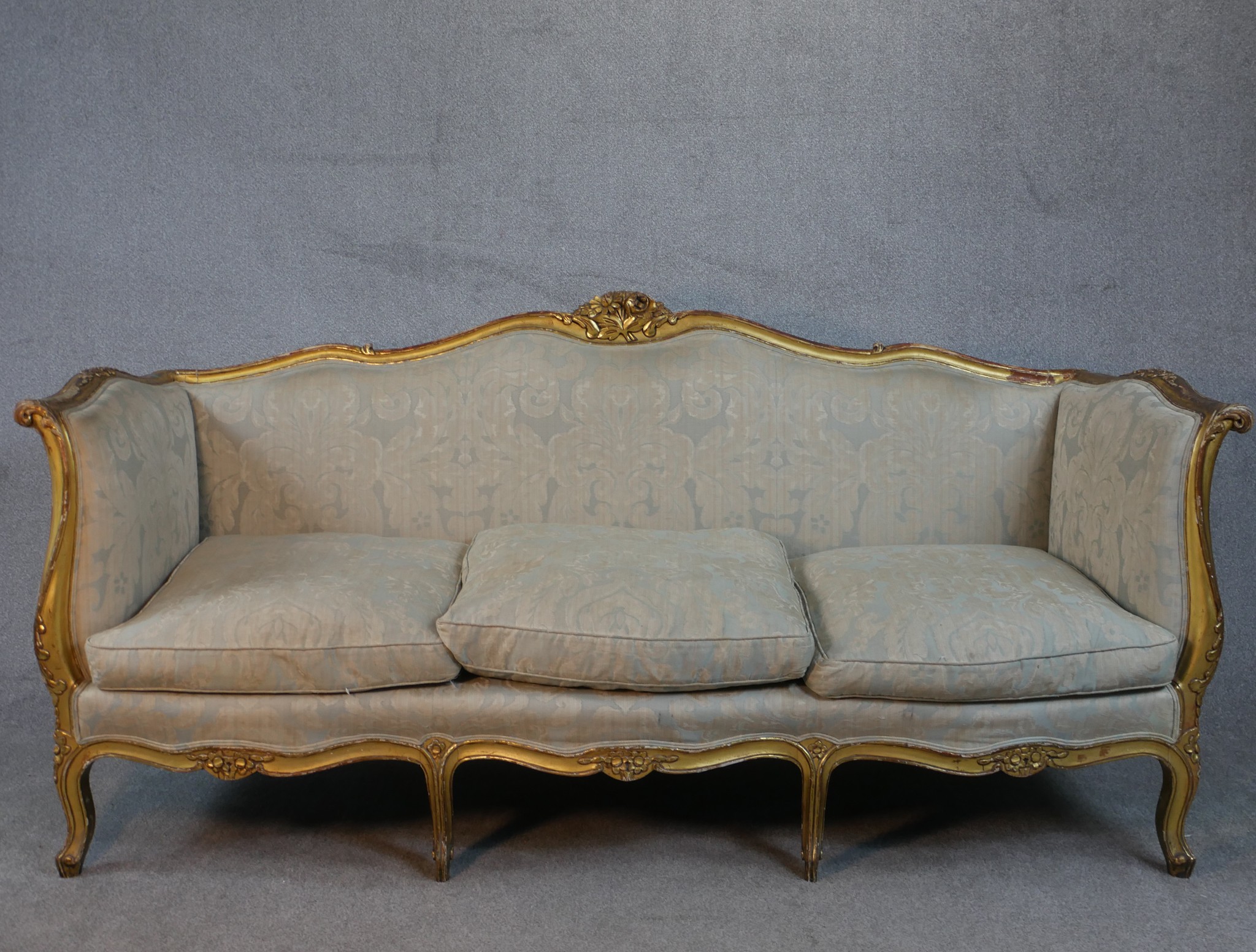 A carved giltwood Louis XV style sofa in floral upholstery on cabriole supports. H.102 W.208 D.76cm