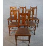 A set of six Arts and Crafts oak dining chairs with pierced foliate central splats on square