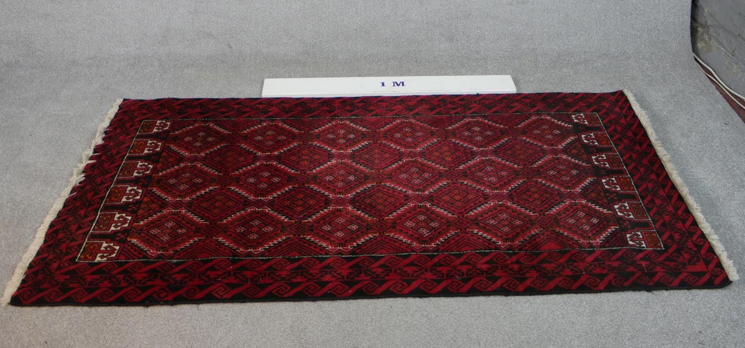 A Persian Meshed rug with repeating lozenge design on a burgundy ground within stylised borders. L. - Image 7 of 7