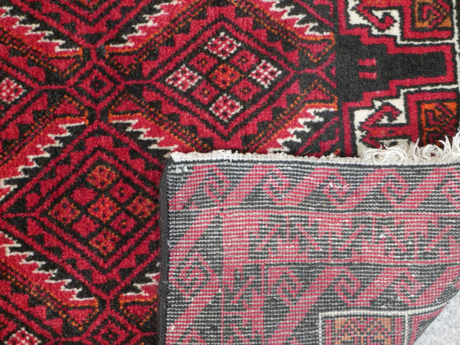 A Persian Meshed rug with repeating lozenge design on a burgundy ground within stylised borders. L. - Image 6 of 7