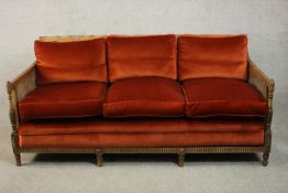 An Edwardian Adam inspired mahogany three seater bergere sofa, upholstered in red velour with