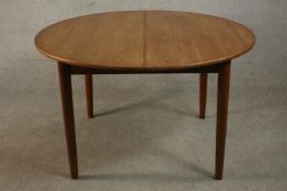 A circa 1960's teak extending dining table with a butterfly leaf, on tapering cylindrical legs. H.73