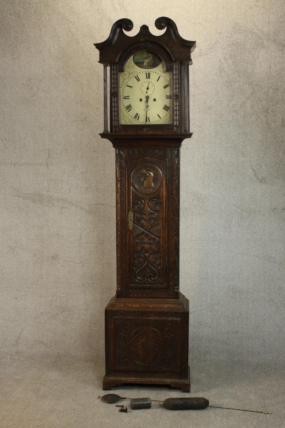 A 19th century carved oak longcase clock, the hood with a swan neck pediment and reeded columns, the