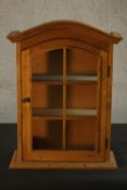 A Dutch style pine wall display cabinet, with an arched top, the door with six glazed panels, with