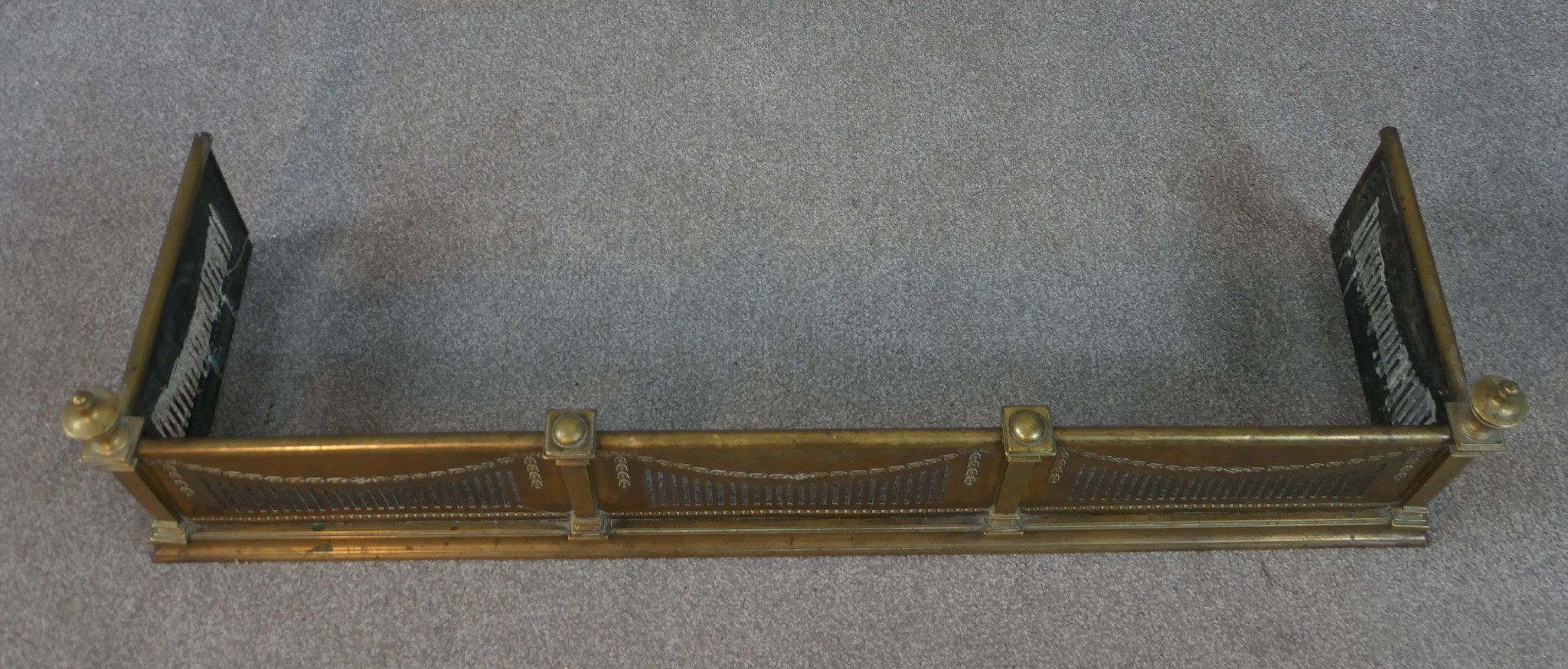 An Adam style pierced brass fender, with urn finials to the corners, decorated with swags and a - Image 2 of 4