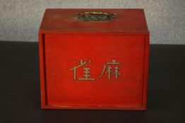 A Chinese bone mah jong set, in a red lacquered box, with a brass handle to the top, the slide out