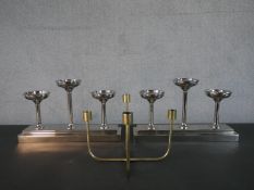 A pair of chrome votive candleholders, each with three holders on a rectangular step down base,