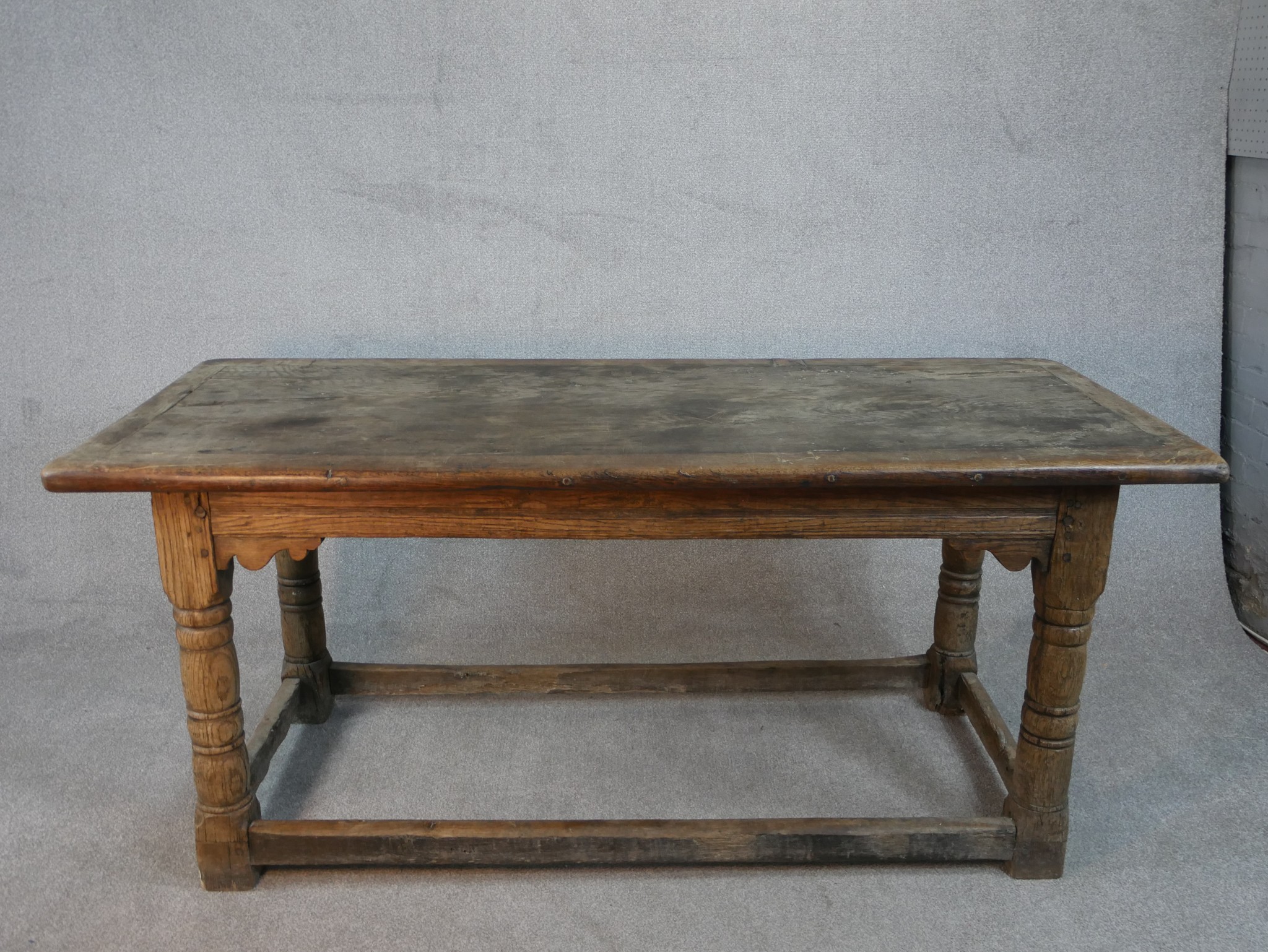 An 18th century oak planked top refectory dining table with cleated ends on turned stretched