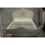 A grey and white painted ornately carved king size bed, the headboard and foot carved and pierced