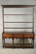 An 18th century oak dresser, the plate rack with three tiers and cup hooks, over three short drawers