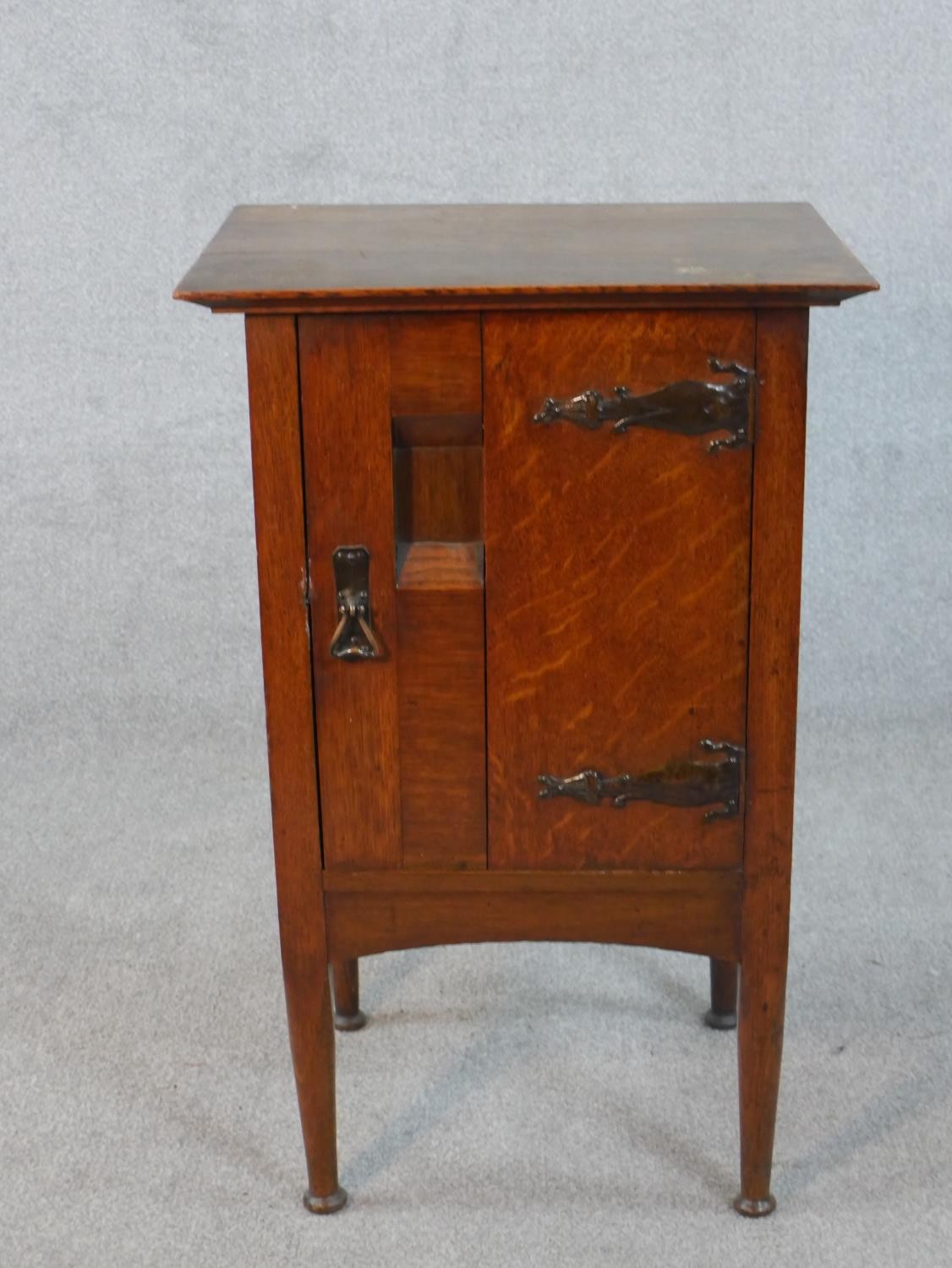 A Harris Lebus Arts and Crafts oak bedside cabinet with recessed panel door on tapering pad foot