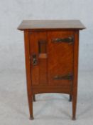 A Harris Lebus Arts and Crafts oak bedside cabinet with recessed panel door on tapering pad foot