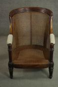 A William IV mahogany caned bergere tub chair, the reeded top rail with carved palm leaves to each
