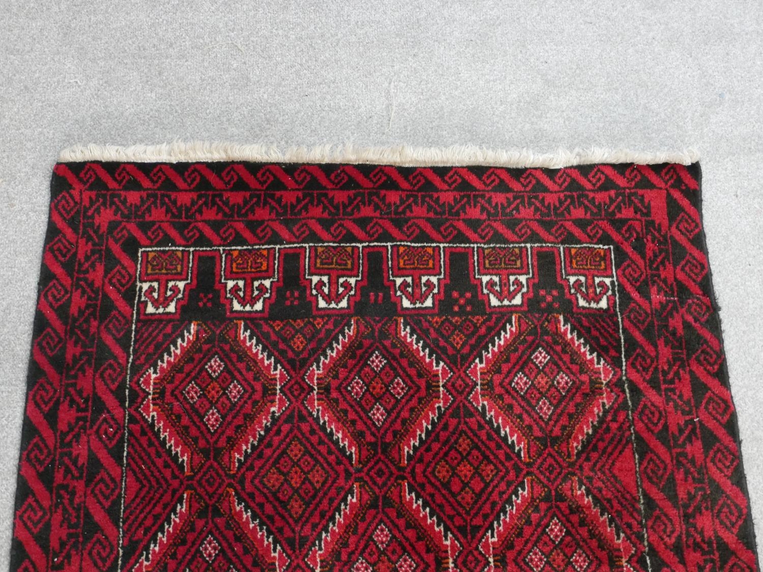 A Persian Meshed rug with repeating lozenge design on a burgundy ground within stylised borders. L. - Image 5 of 7