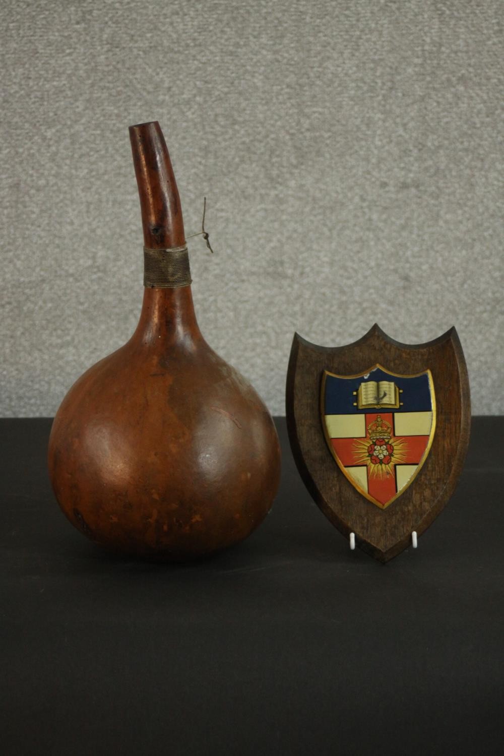 An early 20th century oak heraldic shield with hand painted metal panel to centre with open book and