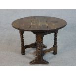 An early 20th century oak Sutherland table, the circular top with two drop leaves, on bobbin