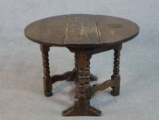 An early 20th century oak Sutherland table, the circular top with two drop leaves, on bobbin