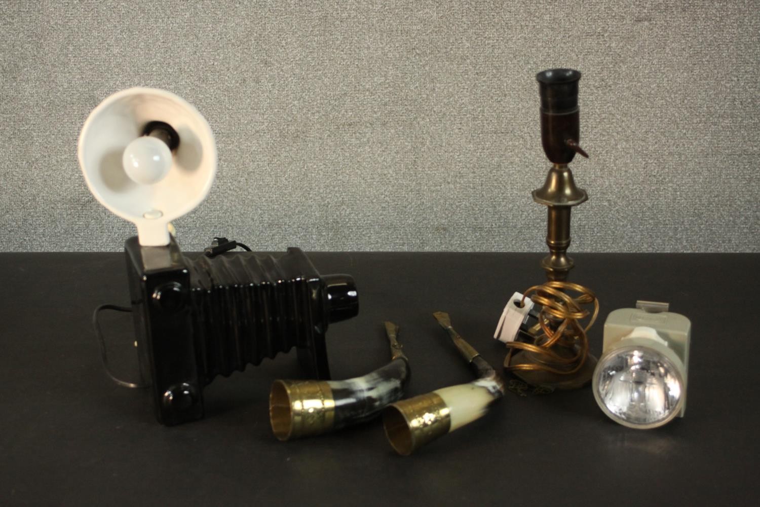 A novelty ceramic table lamp in the form of a vintage camera, along with a brass candle stick