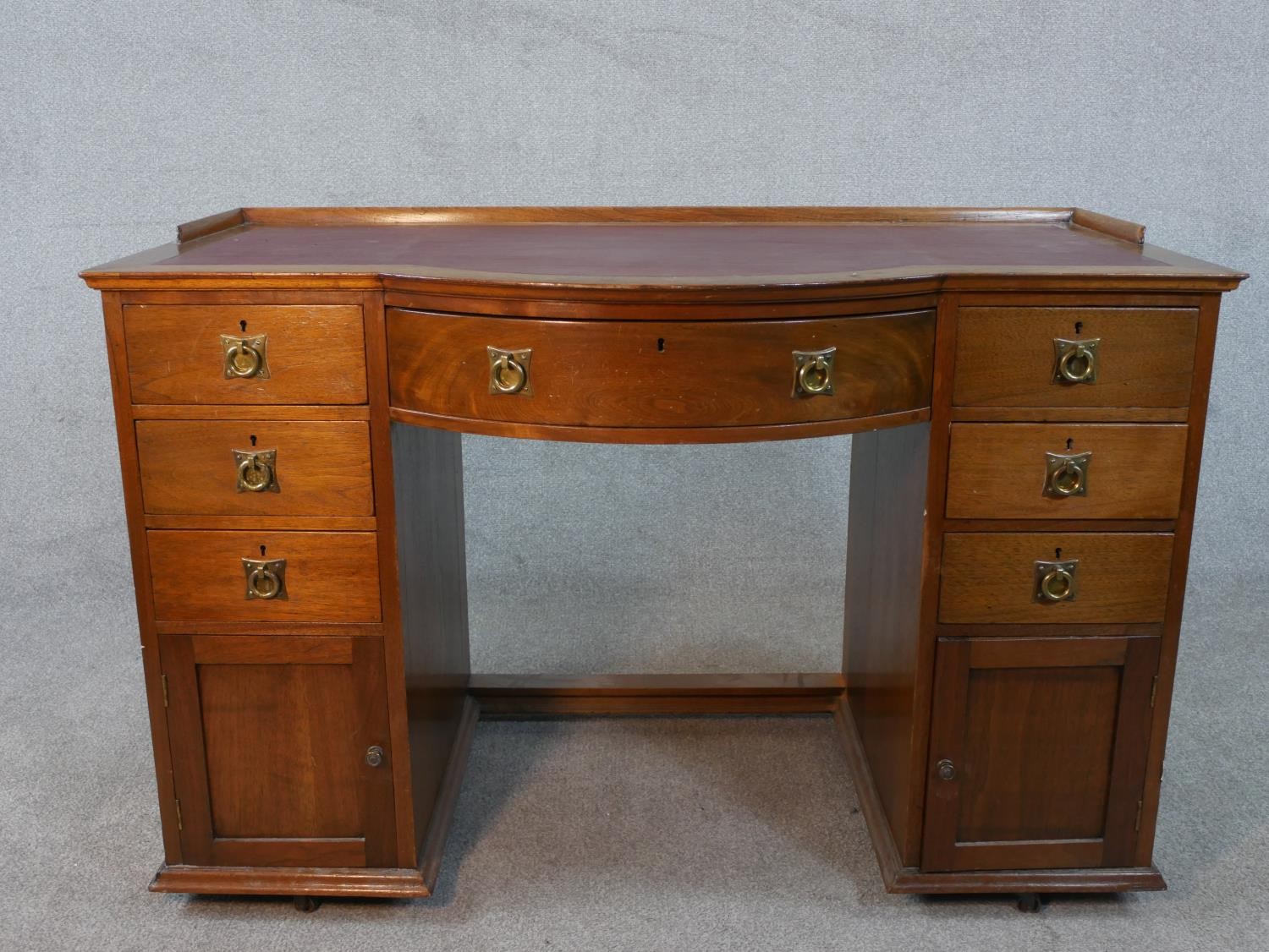 A late 19th century mahogany pedestal desk with bowfronted centre section above drawers and