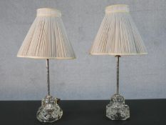 A pair of cut glass table lamps with cream silk pleated lampshades. H.49cm