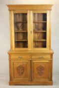 A Victorian style walnut bookcase, the two glazed doors enclosing shelves, over two short drawers