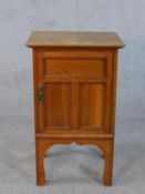 An Arts and Crafts oak bedside cabinet with panel door on shaped supports. H.73 W.45 D.39cm