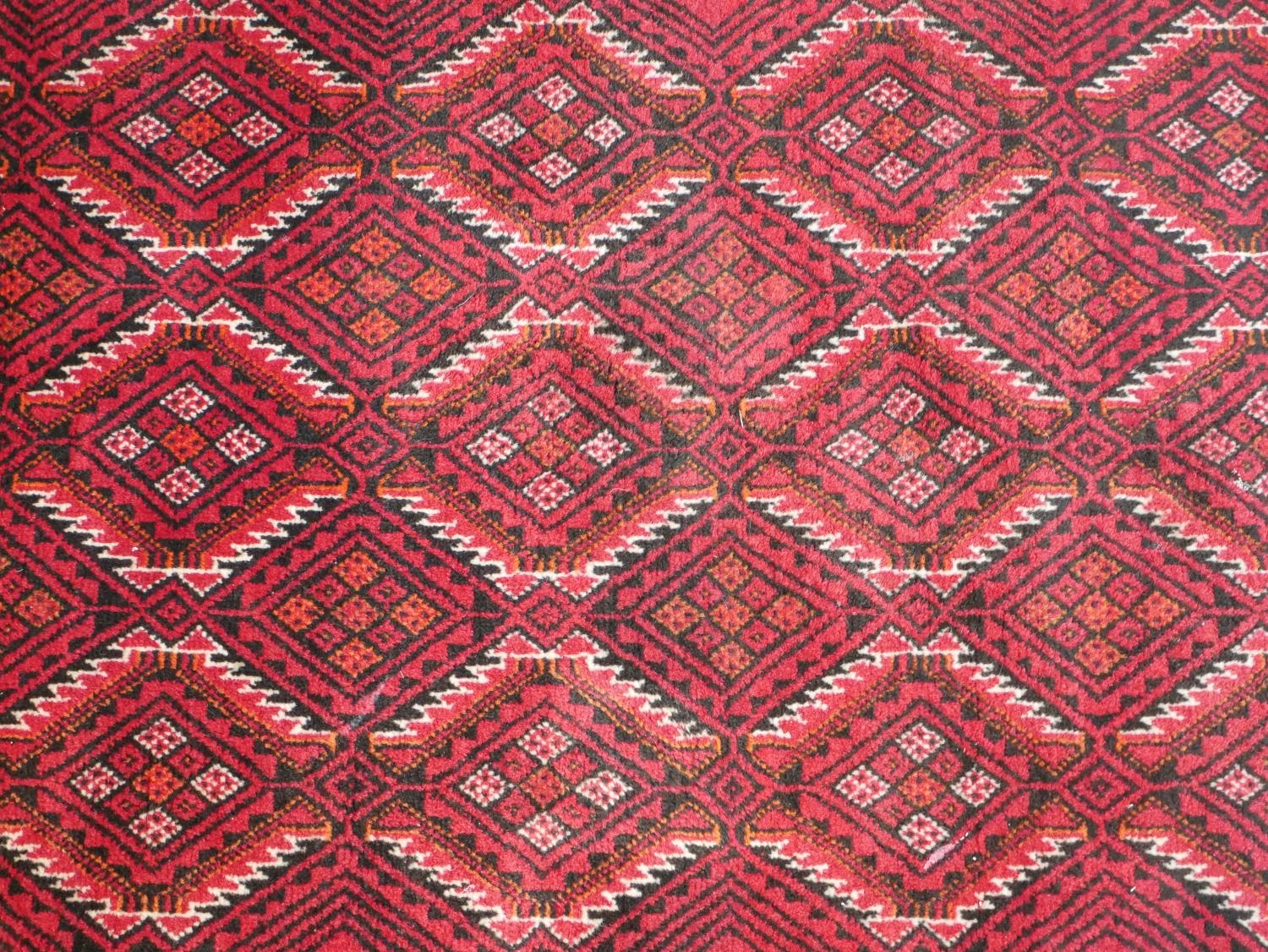 A Persian Meshed rug with repeating lozenge design on a burgundy ground within stylised borders. L. - Image 2 of 7