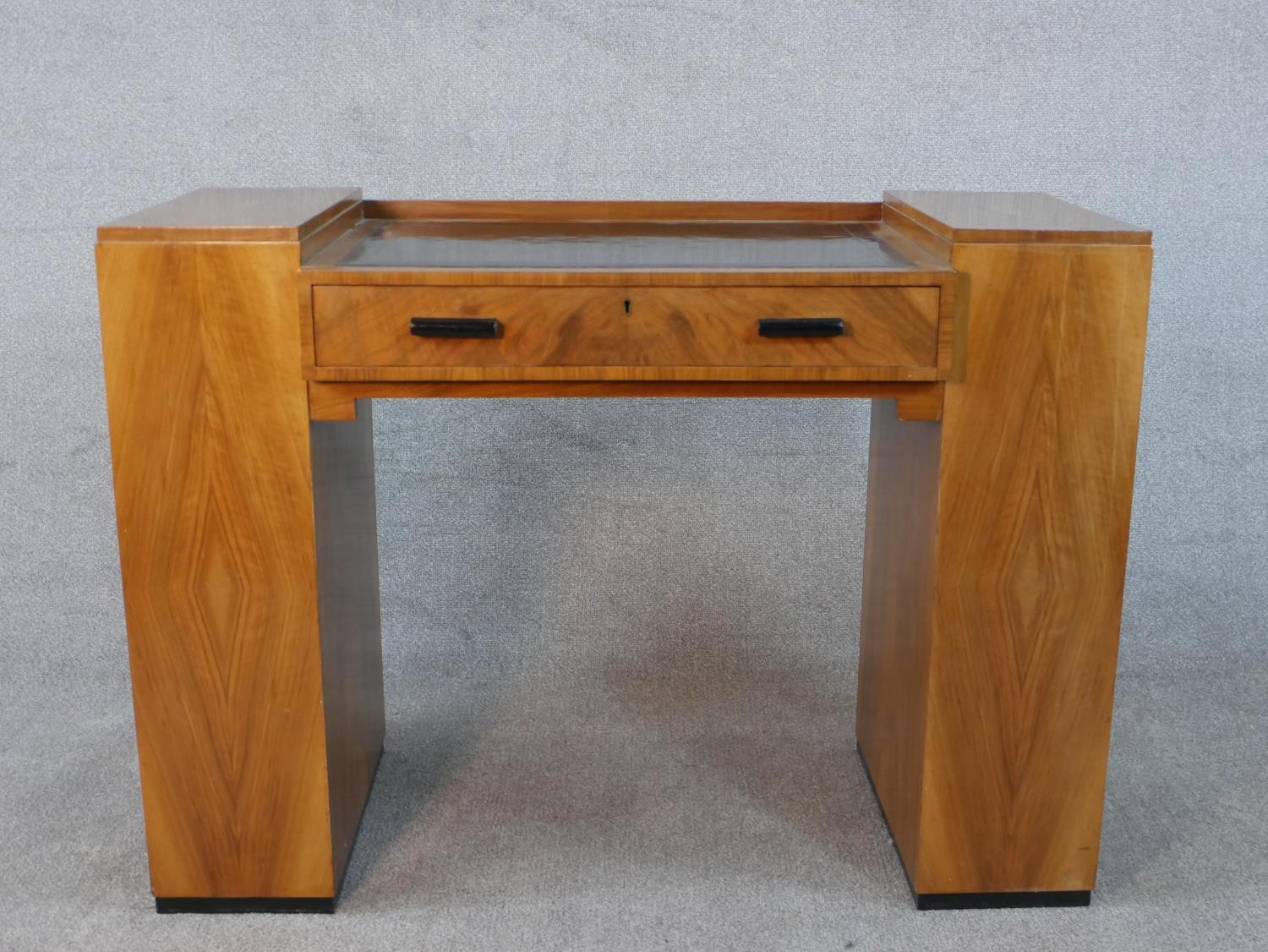 An Art Deco quarter veneered walnut desk with open bookshelves to each pedestal by Maple and Co. H.