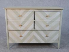 A vintage style chevron decorated chest of four short drawers above a long base drawer raised on