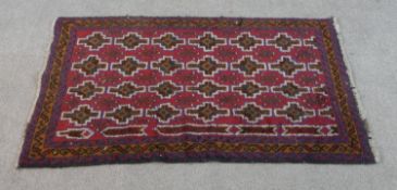A hand made red ground Belouch rug. L.131 W.83cm