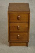 A 1940s Heal's style oak utility bedside chest of three drawers on a plinth base. H.85 W.56 D.48cm.