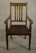 A circa 1900 hardwood open armchair, with a brown leather drop in seat, on square section tapering