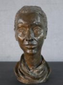 A bronzed moulded head of a lady with her hair up wearing a scarf, indistinctly signed. H.39cm