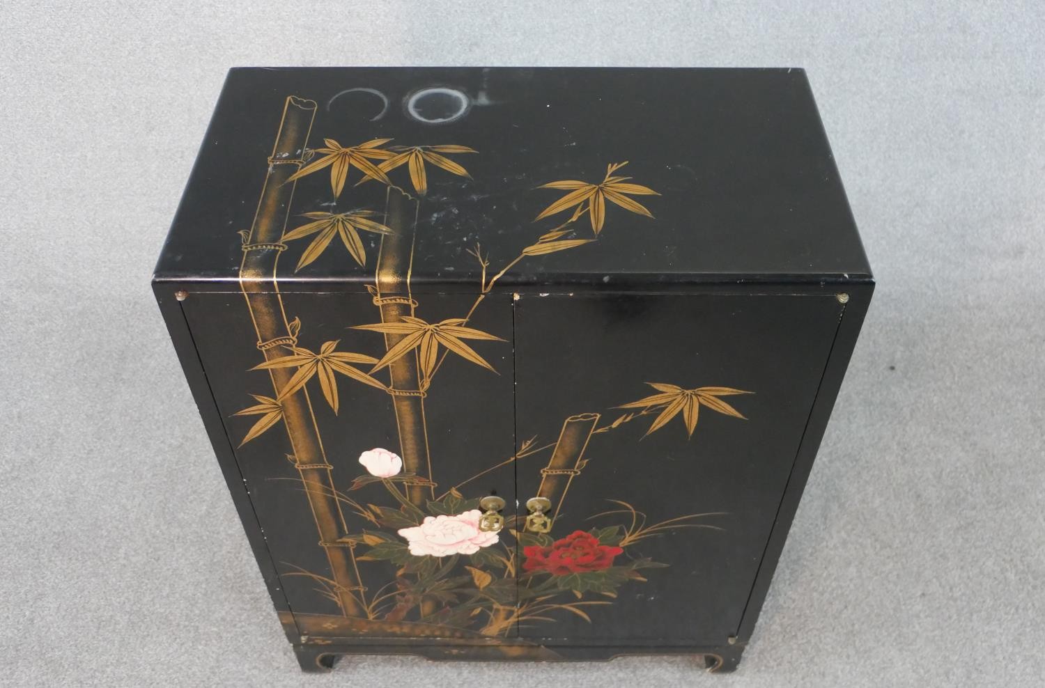 A Chinese peony and bamboo design black lacquered and gilt cabinet with two doors and three - Image 2 of 5