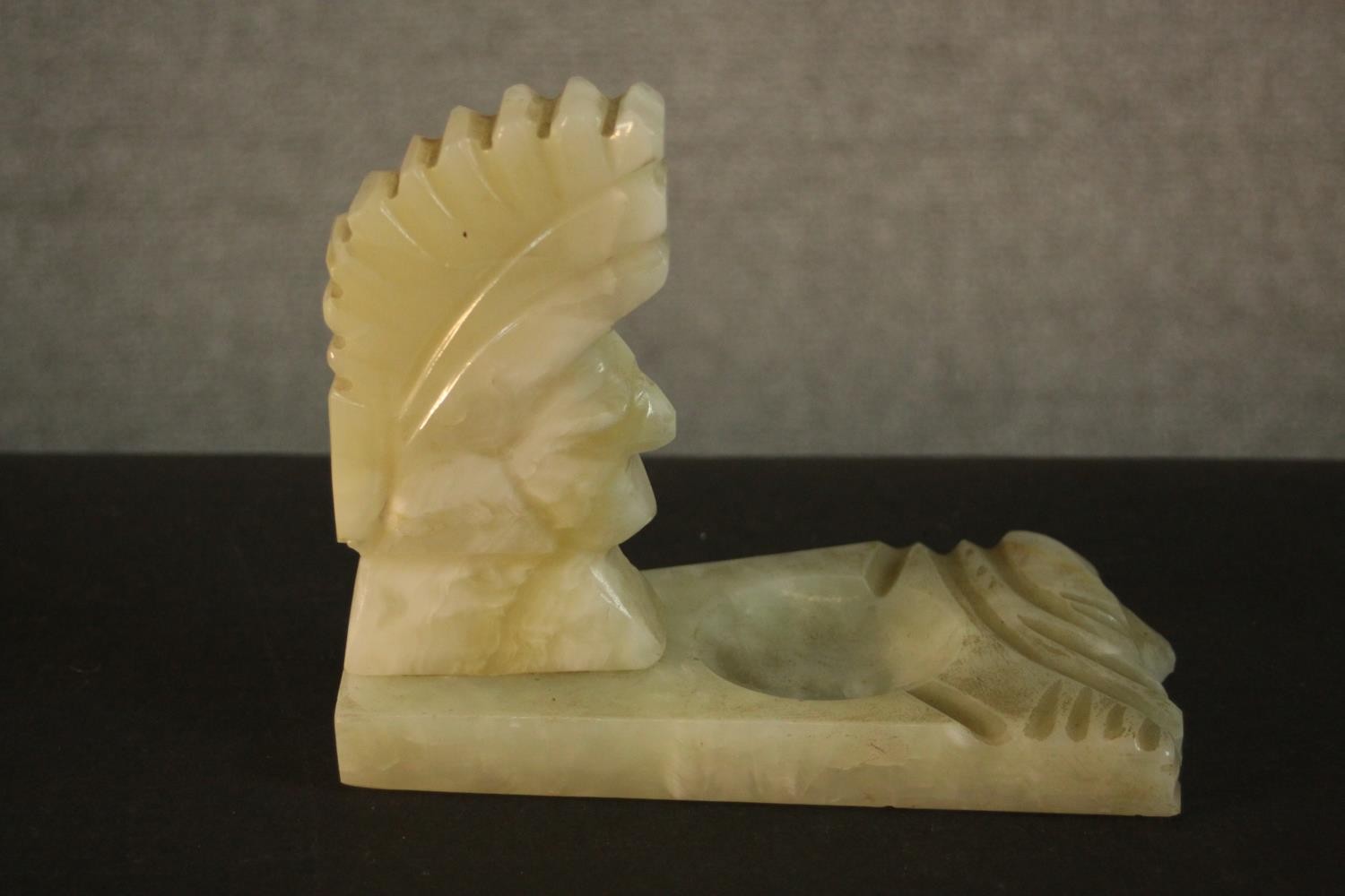 An Art Deco carved alabaster ashtray in the form of a Native American head. H.14 W.17 D.10cm.