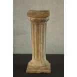 A reconstituted stone garden plinth in the form of a fluted Classical pillar, with a square step