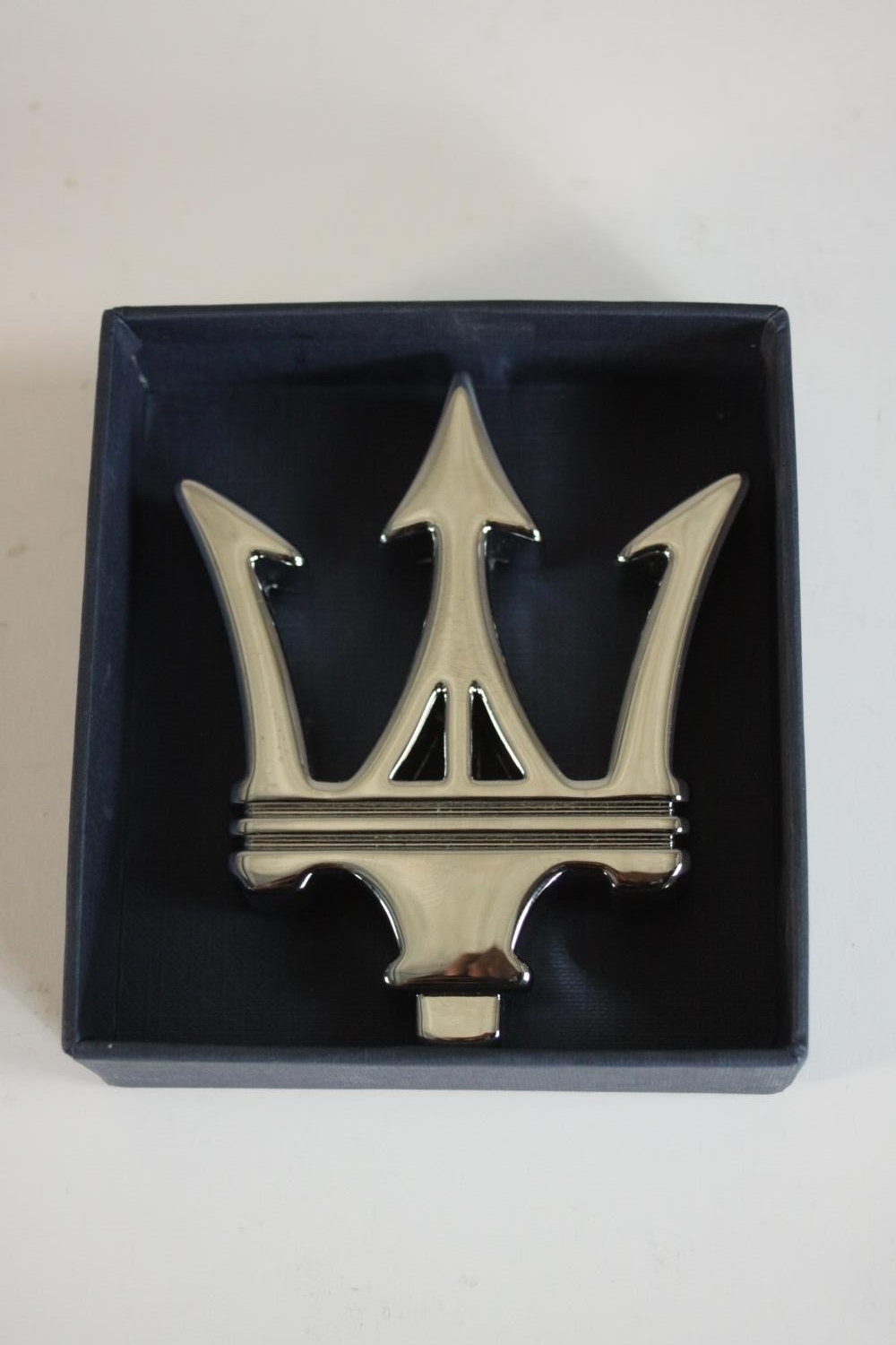 A boxed silver plated Maserati emblem paperweight. H.3 W.10 D.11.5cm. (box).