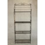 A wrought iron baker's rack, with four shelves, the sides with S shaped scrolling designs. H.194 W.