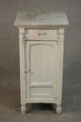 A Continental white painted pine bedside cabinet, with a white marble top over a single drawer and a