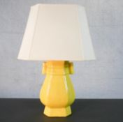 A Chinese yellow glaze vase design table lamp with cream shade. H.61 W.40cm