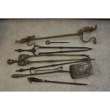 A collection of early 20th century cast iron and brass fire irons, other tools and a cast iron three