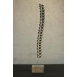 A chrome sculpture modelled as a spine, mounted on a granite base. H.111cm.