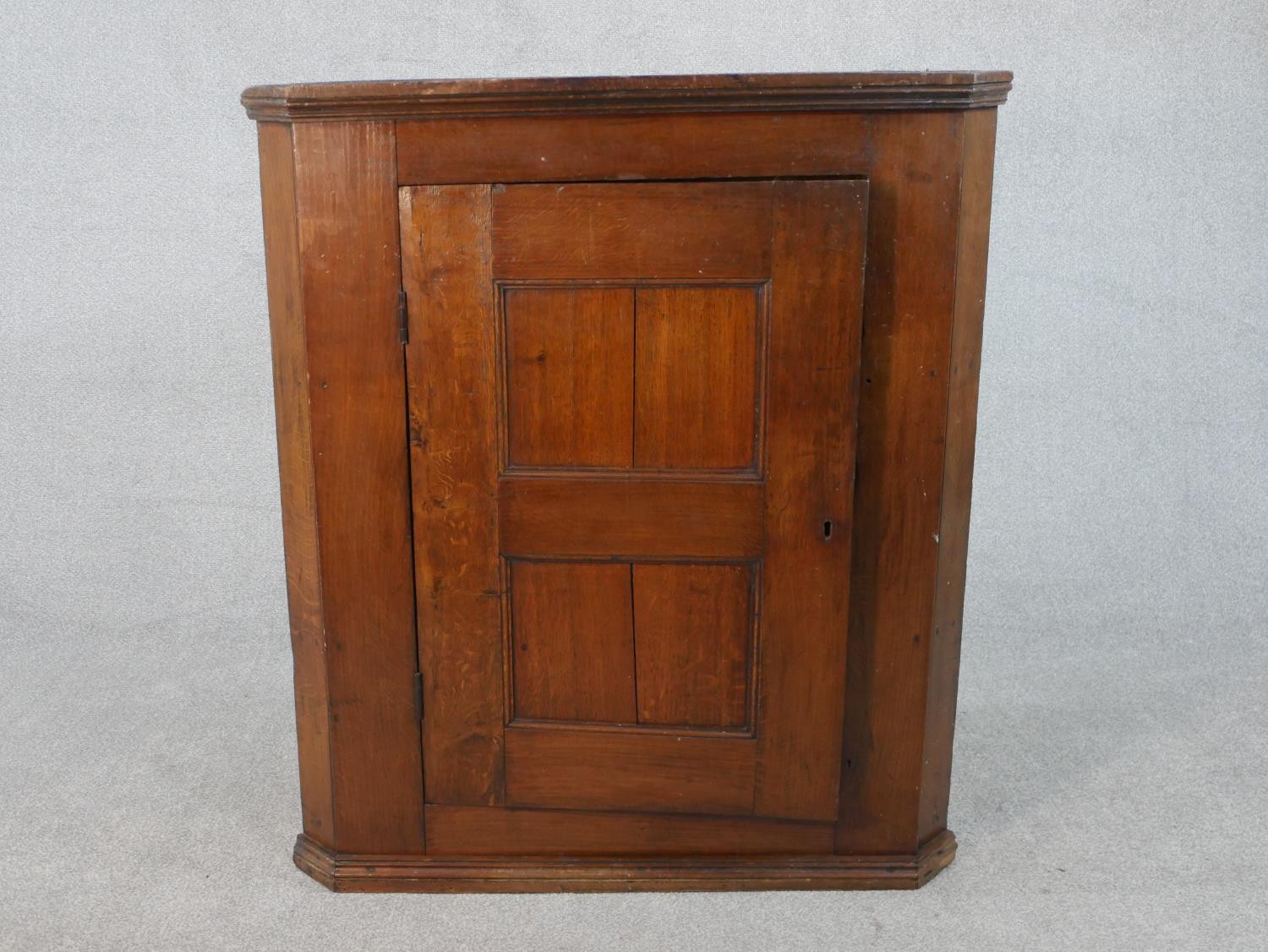 A 19th century oak hanging corner cabinet with panel door enclosing two shelves. H.106 W.94.5 W.46cm