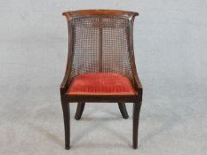 A Regency simulated rosewood bergere type side chair, the carved bar back over caning, above a red